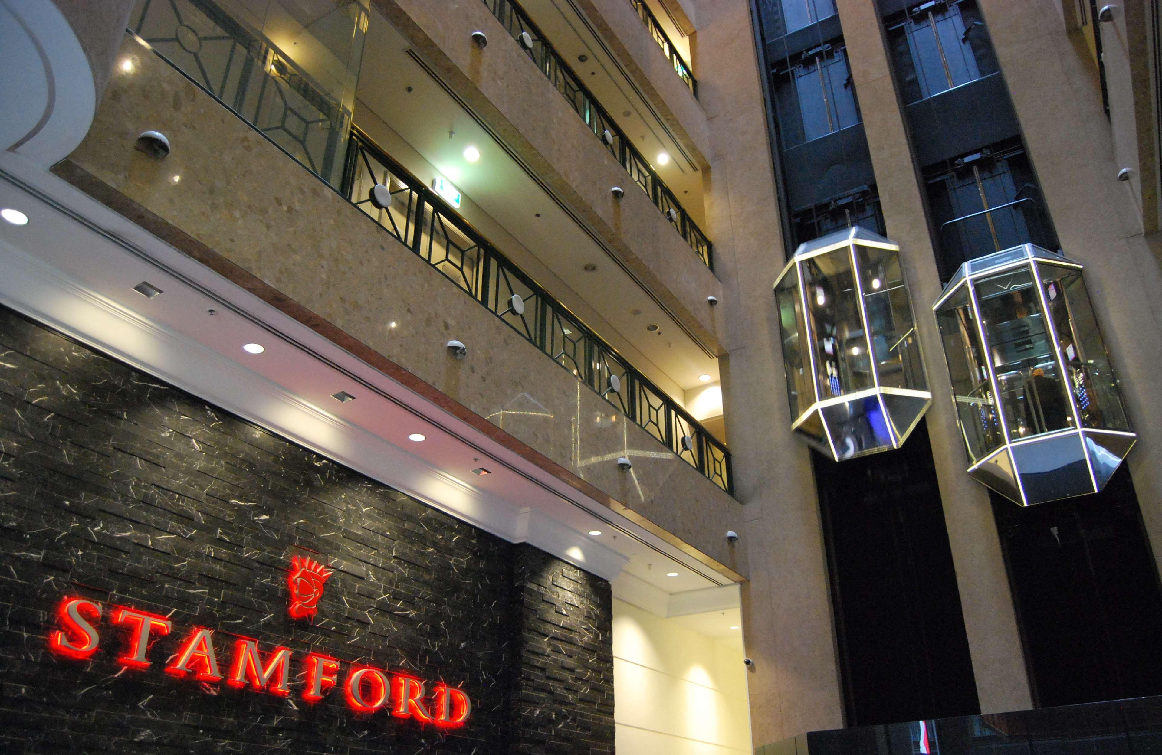 Hotel Stamford Plaza Ville de Melbourne Extérieur photo The photo shows the interior of a building, likely a hotel or commercial space. There is a prominent sign with the name "STAMFORD" in red lettering against a dark stone background. The building features several floors, visible from the photograph, wi