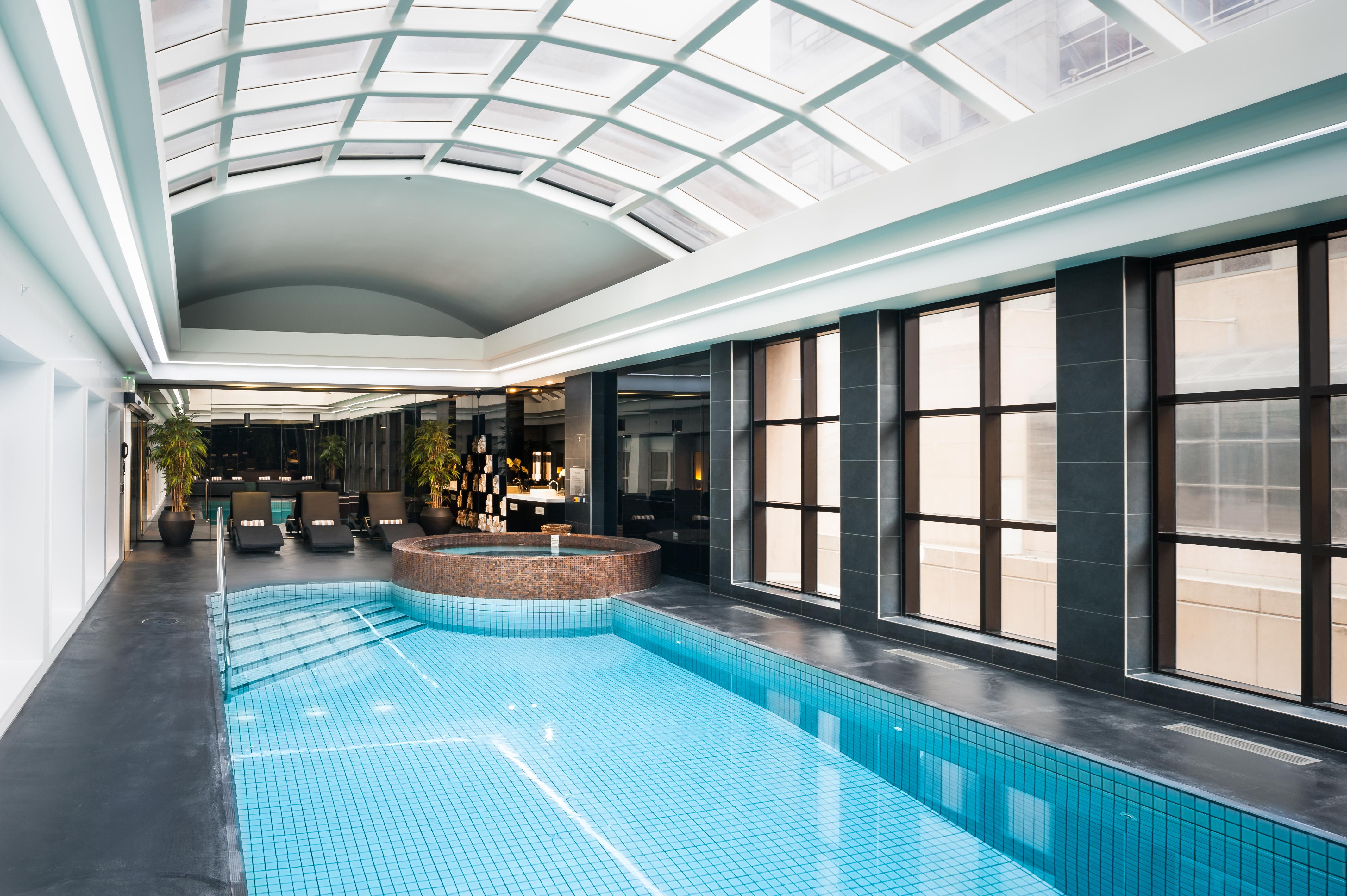 Hotel Stamford Plaza Ville de Melbourne Extérieur photo The photo shows an indoor swimming pool area with a modern and sleek design. The pool is rectangular and features bright blue tiles. Above the pool, there's a large, transparent glass ceiling that allows natural light to flood the space. Surrounding 