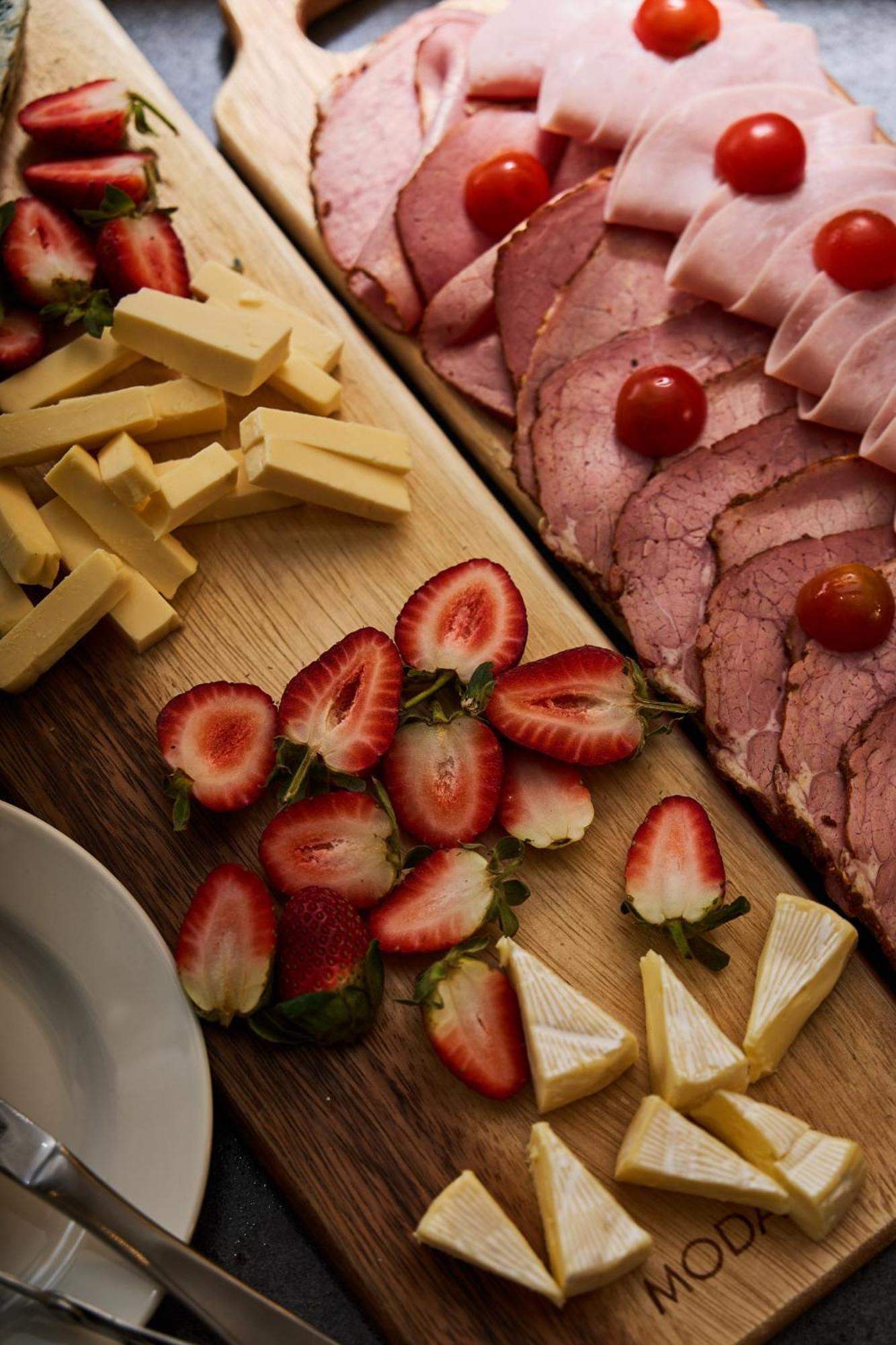 Hotel Stamford Plaza Ville de Melbourne Extérieur photo The photo displays an assortment of food items arranged on a wooden surface. There are slices of various meats, including ham, alongside round cherry tomatoes. Next to the meat, there are several pieces of yellow cheese cut into sticks. Additionally,