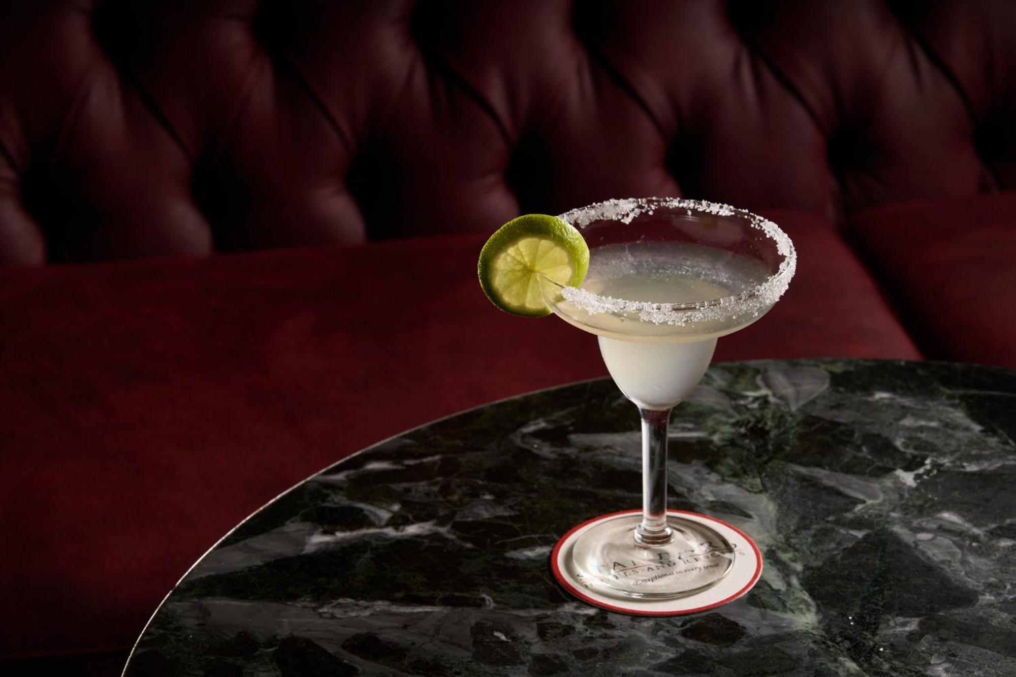 Hotel Stamford Plaza Ville de Melbourne Extérieur photo The photo shows a beautifully presented margarita cocktail served in a classic margarita glass. The drink is clear with a salt rim around the edge, and adorned with a slice of lime. The glass is placed on a dark green marble table, contrasting with a