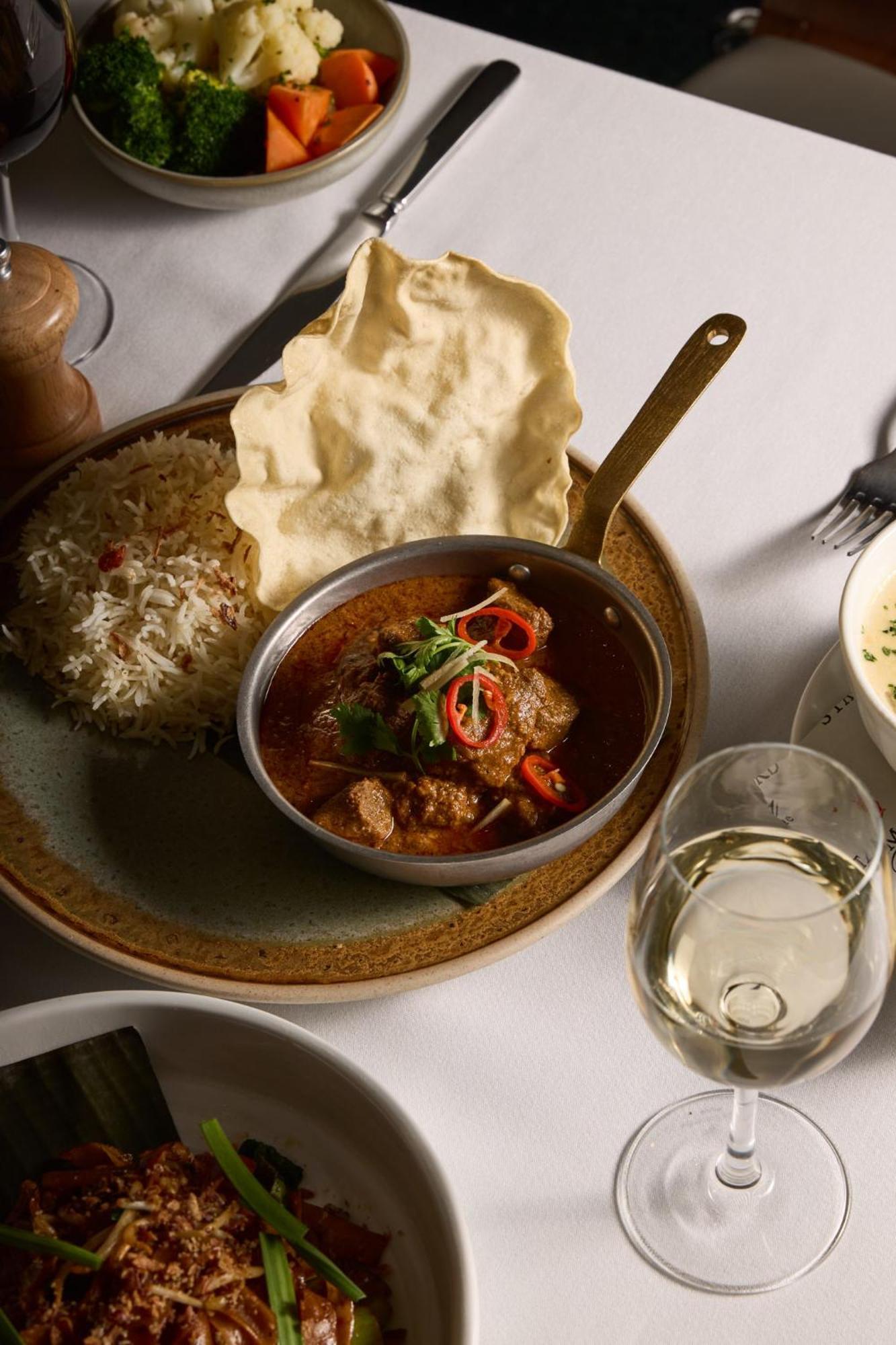 Hotel Stamford Plaza Ville de Melbourne Extérieur photo The photo features a plated meal that includes a serving of meat curry in a small round dish. The curry is garnished with herbs and slices of chili. Accompanying the curry, there is a mound of fluffy rice, and a piece of crispy flatbread (poppadom) r