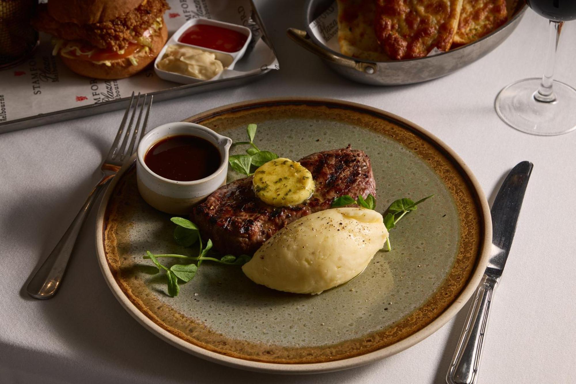 Hotel Stamford Plaza Ville de Melbourne Extérieur photo The photo shows a well-presented plate featuring a serving of steak, topped with a dollop of herb butter and surrounded by fresh sprouts or microgreens. There is a smooth portion of mashed potatoes beside the steak, and a small bowl of sauce, likely 