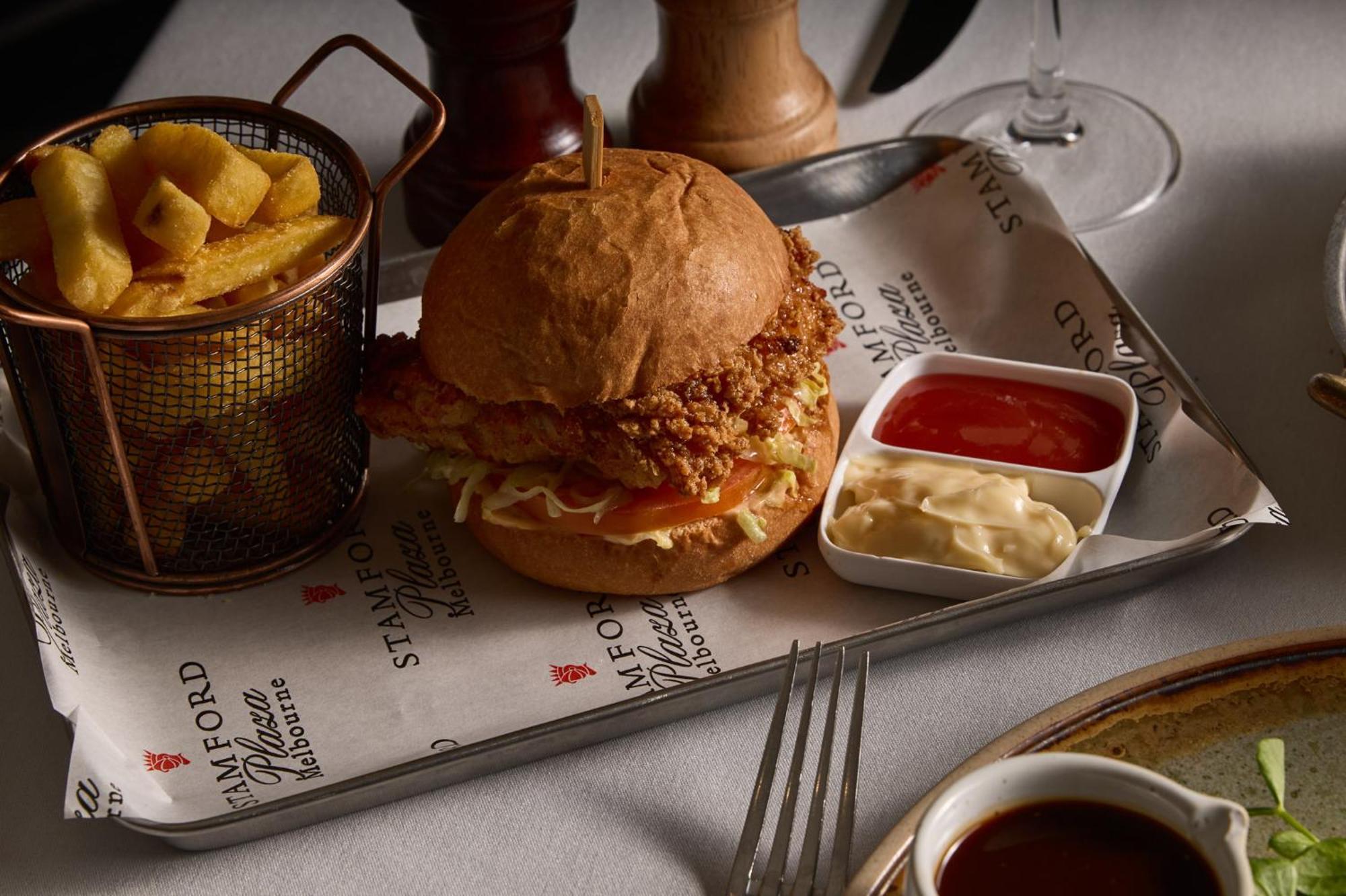 Hotel Stamford Plaza Ville de Melbourne Extérieur photo The photo features a meal served on a tray. In the center is a sandwich made with a golden-brown chicken fillet that appears crispy, placed inside a soft bun. The sandwich is likely complemented by some type of sauce or condiments underneath the chic