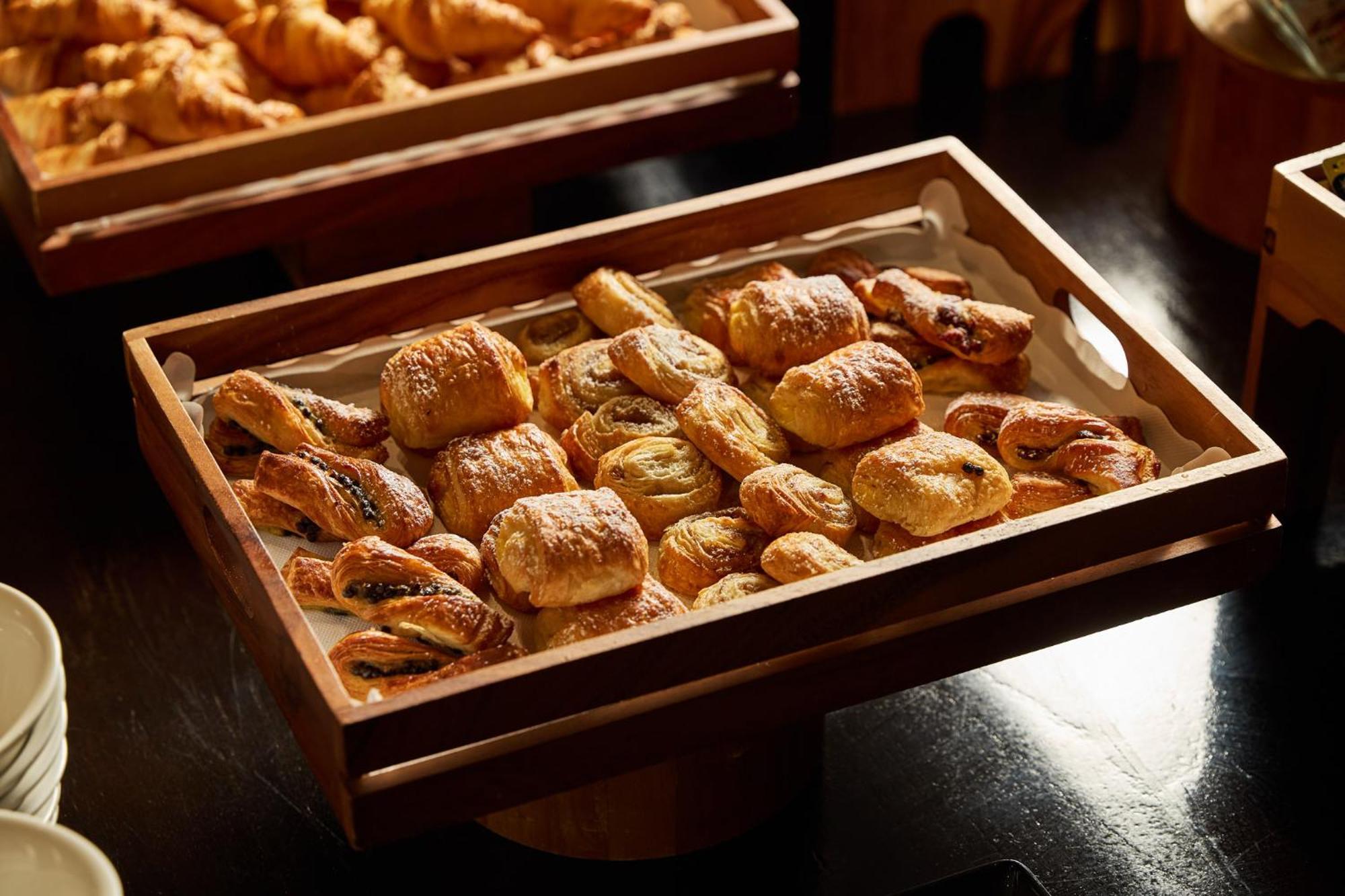 Hotel Stamford Plaza Ville de Melbourne Extérieur photo The photo shows a wooden tray filled with an assortment of baked goods. There are various types of pastries, including small, flaky items that appear to be puff pastries, and possibly some filled with chocolate or fruit. The pastries are golden brown