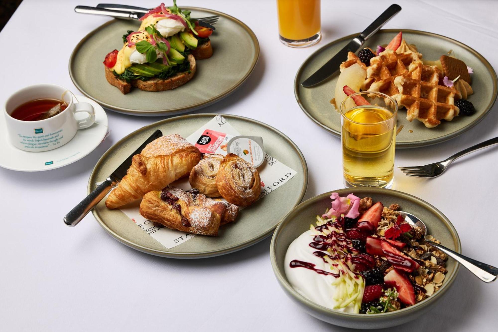 Hotel Stamford Plaza Ville de Melbourne Extérieur photo The photo displays a variety of breakfast items arranged on several plates. 

1. **Top-left Plate**: Features an open-faced sandwich with avocado, topped with poached eggs and garnished with vegetables.
2. **Top-right Plate**: Contains freshly made w