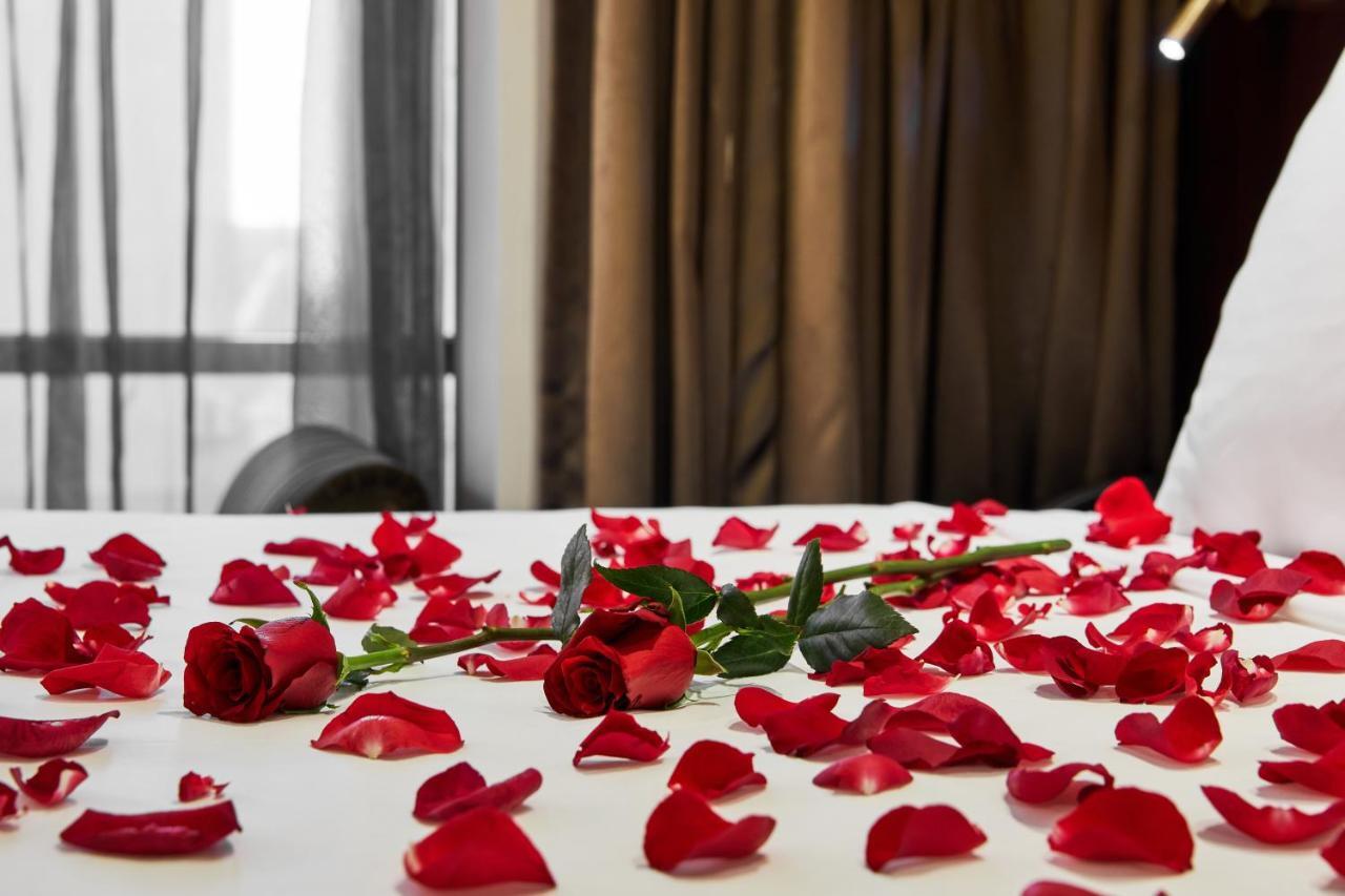 Hotel Stamford Plaza Ville de Melbourne Extérieur photo The photo shows a bed or a table covered with scattered red rose petals. Among the petals, there are a few whole red roses, still with their stems. The background features curtains that appear to be sheer, allowing some light to come through, and the